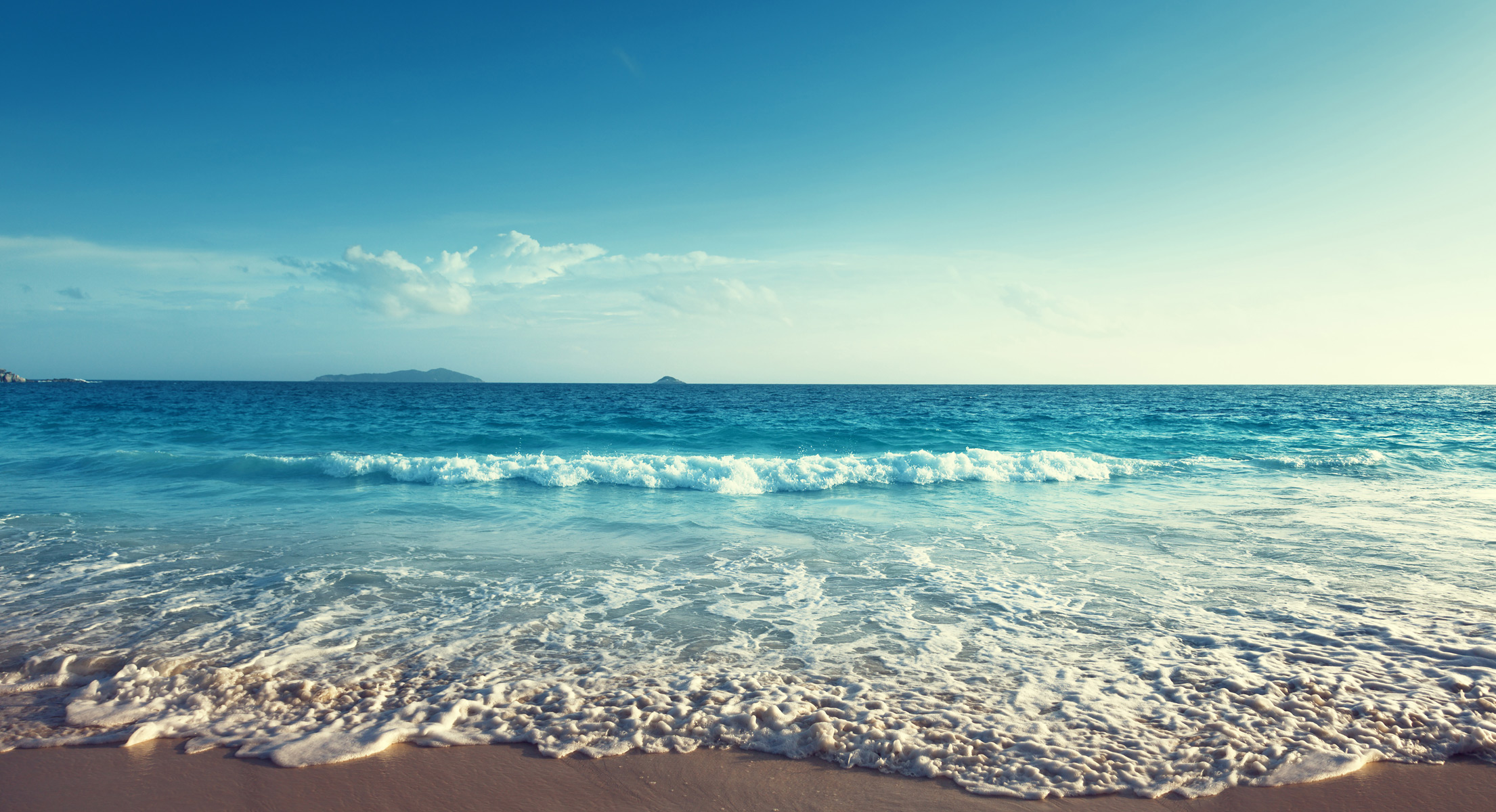 the waves slowing coming into a sandy beach