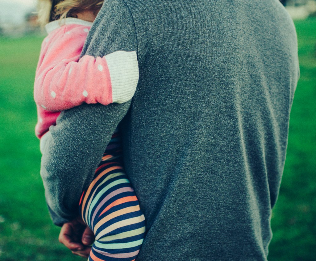 a parent holding a child in their arms outside