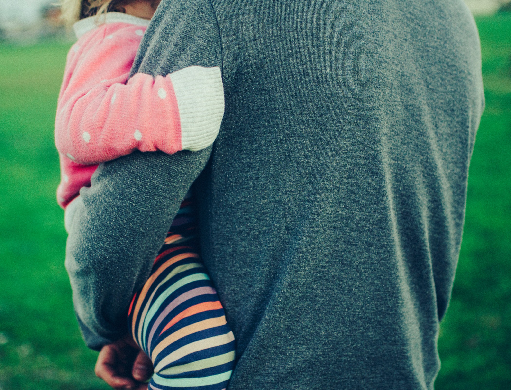 a parent holding a child in their arms outside